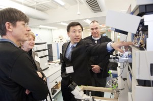 Daniel Dai, second from right, a Prin­cipal Research Sci­en­tist at the Bar­nett Insti­tute, gives a tour of the facility. Photo by Brooks Canaday.