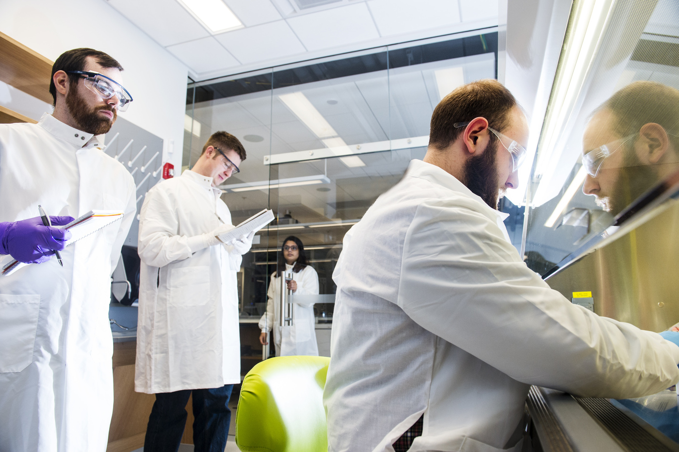 Three male students working at a hood in a lab.