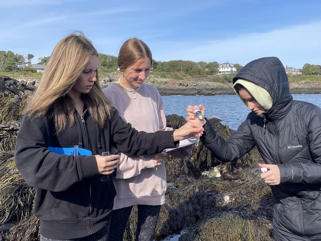 Three young female students dropping liquid into a pipette