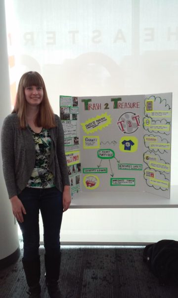 Sarah Braun stands in front of a poster for Trash to Treasure