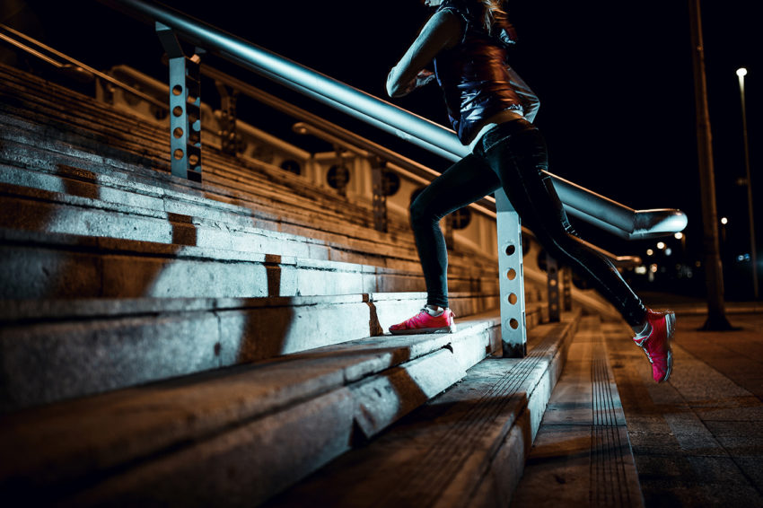 Young woman running at night in a urban city area