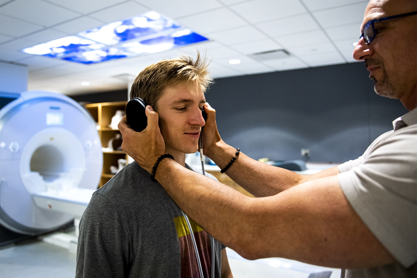 08/06/19 - BOSTON, MA. - Student Kieran McVeigh demonstrates how headphones are used for Psyche Loui and Ajay Satpute’s research on the relationship between musical anhedonia and autism spectrum disorders in the Biomedical Imaging Center in the Interdisciplinary Science and Engineering Complex on August 06, 2019. Photo by Ruby Wallau/Northeastern University