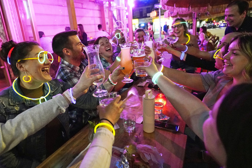 people out at a bar raising glasses in a toast