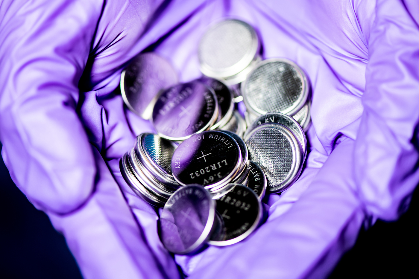 close up image of batteries in a purple gloved hand
