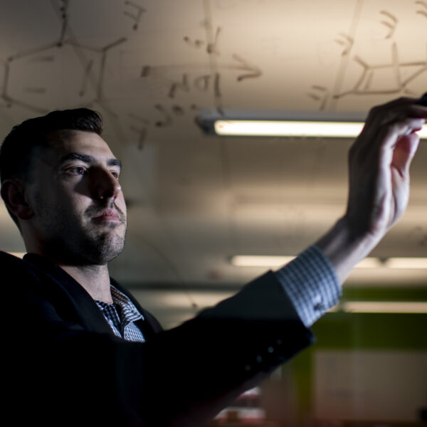 Steven Lopez is photographed writing on dry erase board.