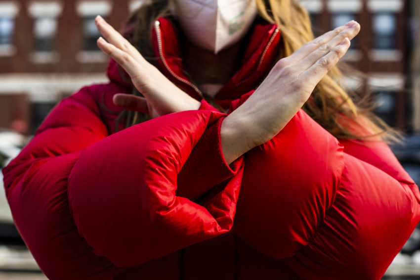 a girl in a red jacket holds her arms up in an "X" shape