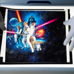 Gloved hands placing a translucent star wars poster onto a light table