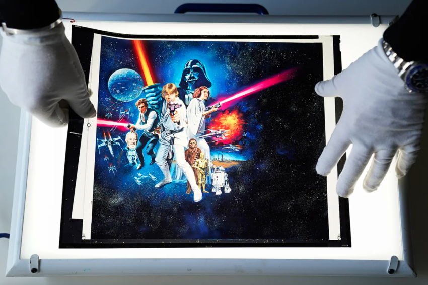 Gloved hands placing a translucent star wars poster onto a light table