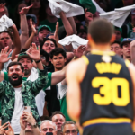 a basketball player stands out of focus in front of a cheering crowd