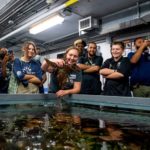 Students from Boston's We Belong hold a lobster