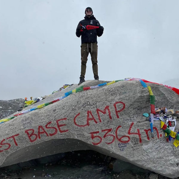 Alexander Anderson stands on Everest base camp rock