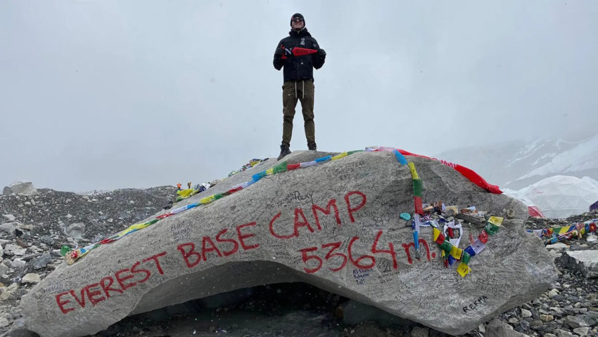 Alexander Anderson stands on Everest base camp rock
