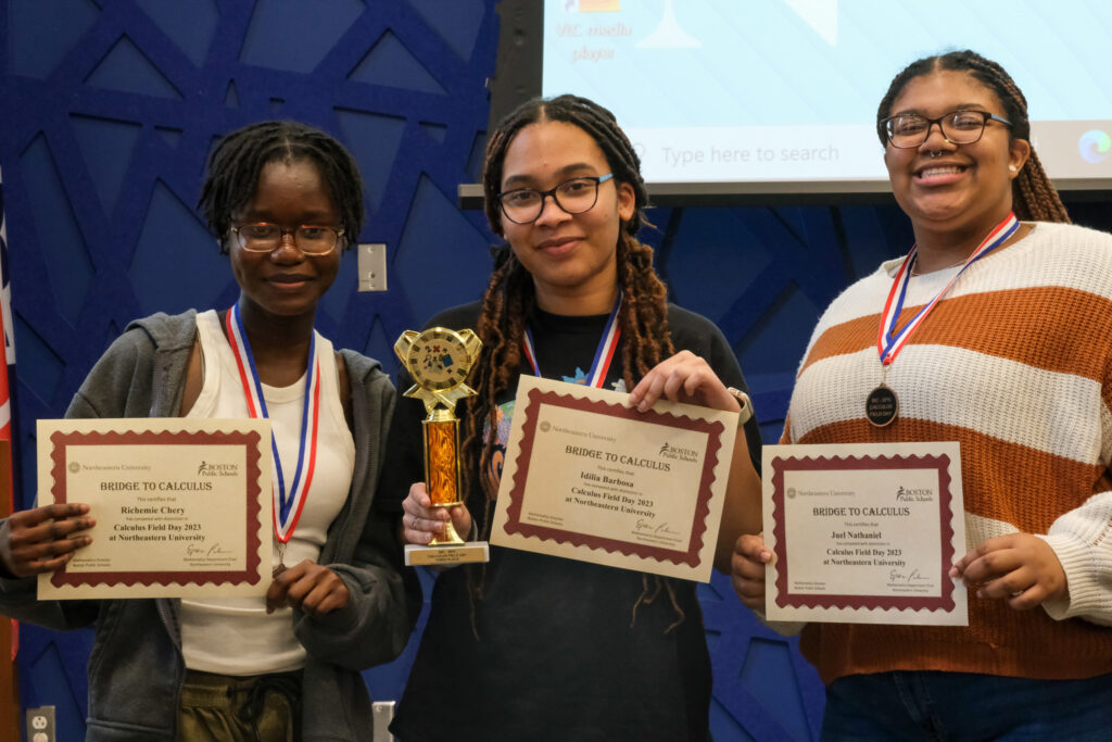 Three high school student displaying achievement certificates and medals