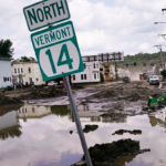 A highway sign in Vermont surrounded by flooding.