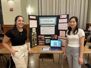 Students representing COSSDAC stand around a poster advertising the student organization. 