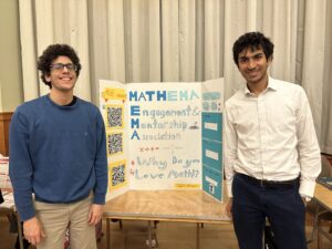 Students representing MathEMA stand around a poster advertising the student organization. 