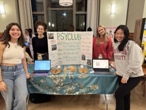 Students representing PsyClub stand around a poster advertising the student organization. 