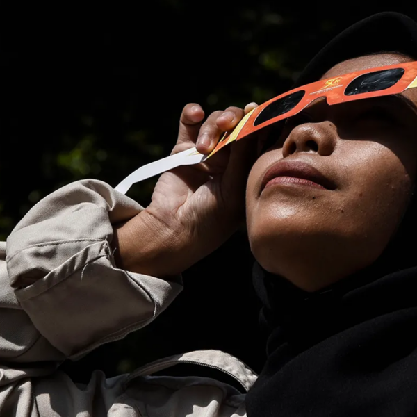 A woman looks at an eclipse using protective eyewear.