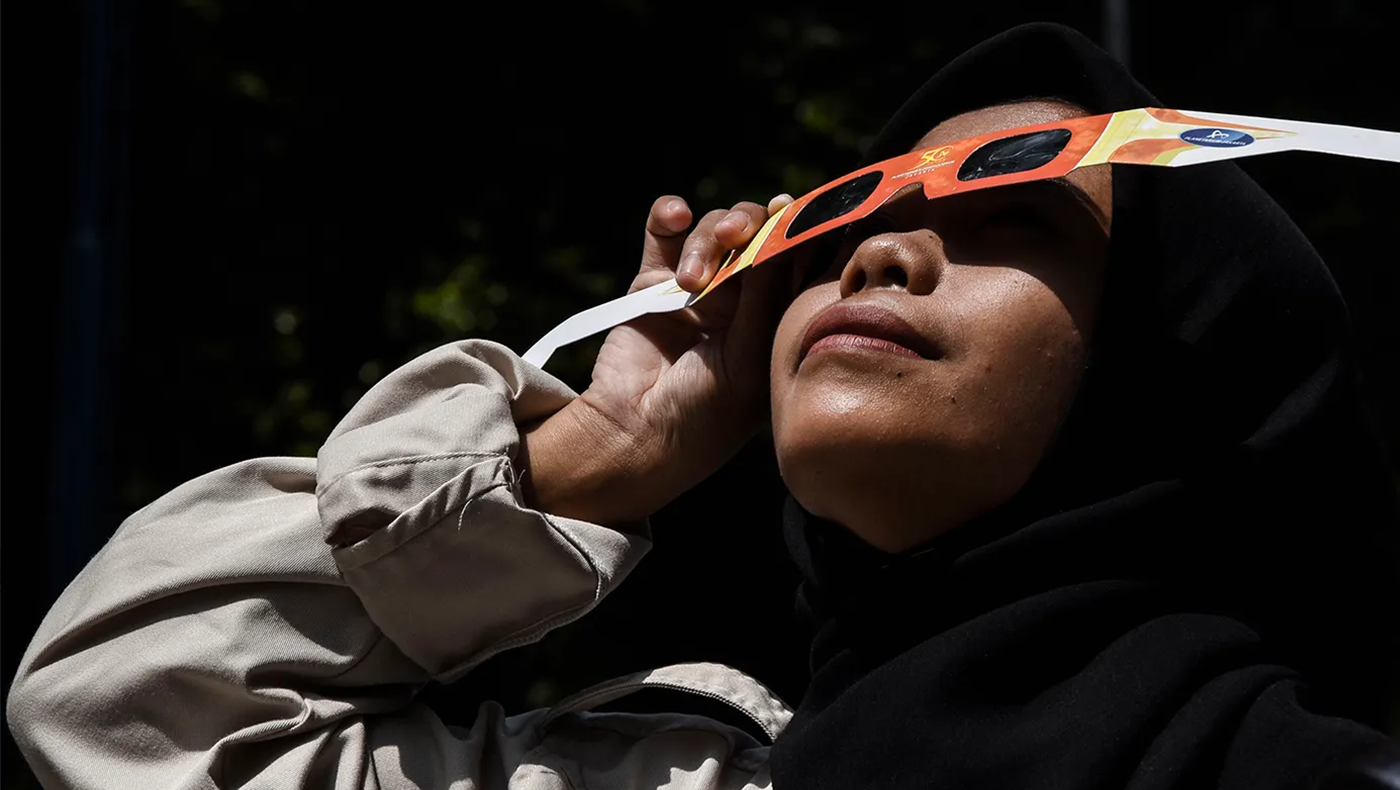 A woman looks at an eclipse using protective eyewear.