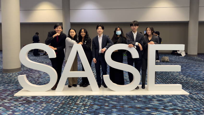 Members of the Northeastern Chapter of the Society of Asian Scientists and Engineers (SASE) stand in front of a sign that reads SASE.