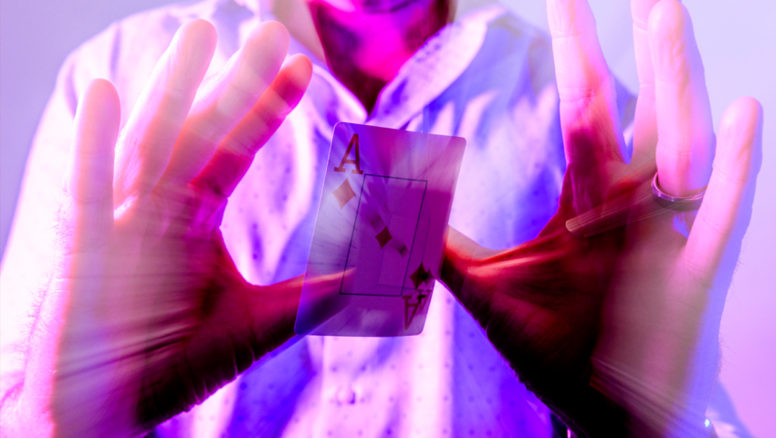 A man holds up his hands while a playing card floats in between them.