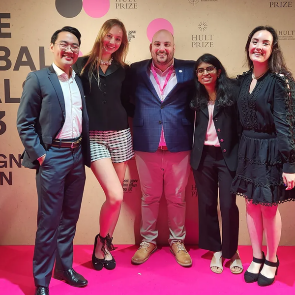 Students represent Northeastern at the global finals of the Hult Prize. Five people pose together on a pink carpet.