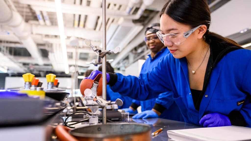 Scientist in a blue lab coat conducts experiment