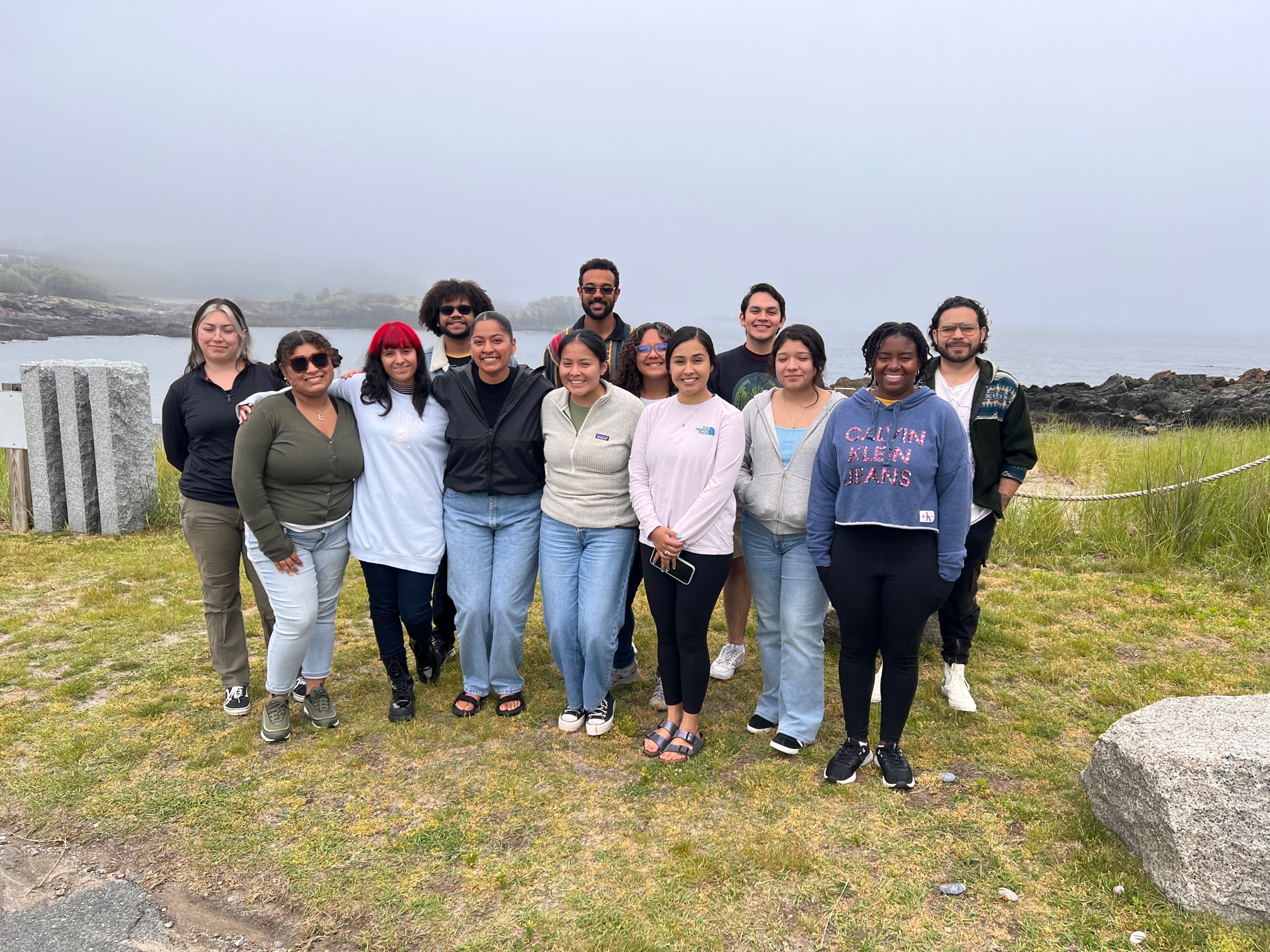 Group photo of students gathered together in front of a foggy cliff, overlooking the ocean.