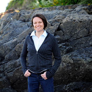 Katie Lotterhos standing outdoors in front of a rocky cliff
