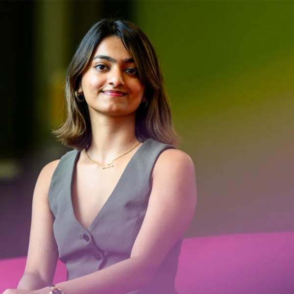 Picture of a young woman in a vest sitting on a purple chair.